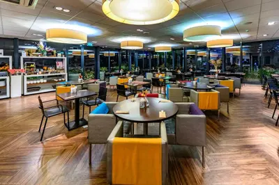 a restaurant with tables and chairs in a cafeteria at Grand Hotel Amstelveen in Amstelveen