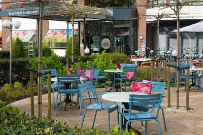 a group of tables and chairs in front of a restaurant at Grand Hotel Amstelveen in Amstelveen