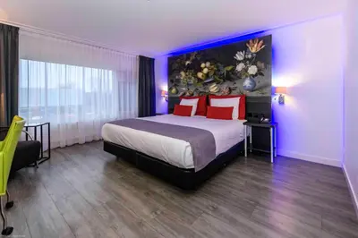 a bedroom with a large bed with red pillows at Grand Hotel Amstelveen in Amstelveen