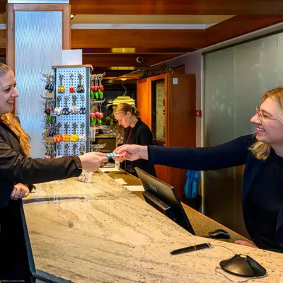 two women standing at a counter shaking hands at Grand Hotel Amstelveen in Amstelveen