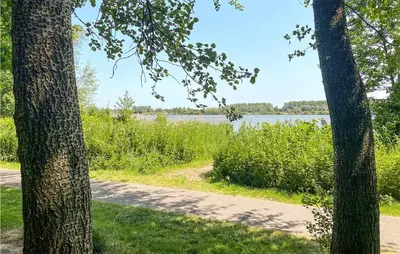 a path next to a lake with two trees at Stunning Home In Noordwijk With Wifi in Noordwijk aan Zee