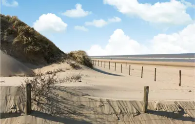 a sandy beach with a fence in front of the ocean at Stunning Home In Noordwijk With Wifi in Noordwijk aan Zee