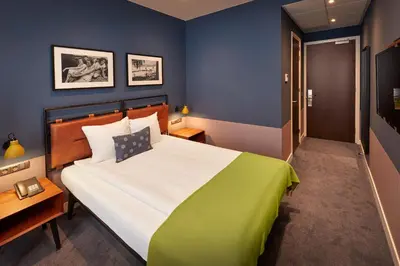 a bedroom with a large bed with a green blanket at Hotel Lion D'Or in Haarlem