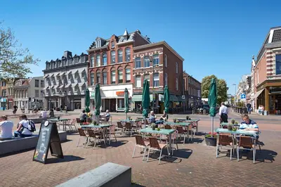 a group of people sitting at tables on a city street at Hotel Lion D'Or in Haarlem