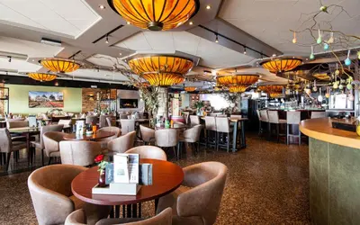 a restaurant with tables and chairs and chandeliers at Hotel Old Dutch in Volendam