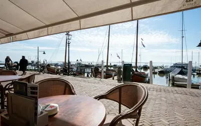 a view of a marina with tables and chairs and boats at Hotel Old Dutch in Volendam