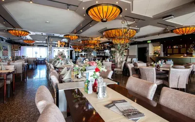 a dining room with tables and chairs and chandeliers at Hotel Old Dutch in Volendam