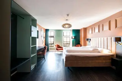 a bedroom with a bed and a desk and chairs at Hotel Old Dutch in Volendam