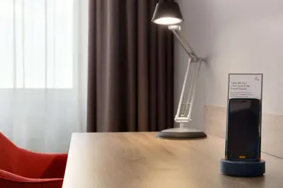 a cell phone on a table next to a lamp at Ramada by Wyndham Amsterdam Airport Schiphol in Badhoevedorp