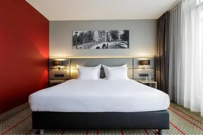 a bedroom with a large white bed with red walls at Ramada by Wyndham Amsterdam Airport Schiphol in Badhoevedorp