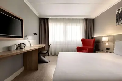 a hotel room with a bed and a red chair at Ramada by Wyndham Amsterdam Airport Schiphol in Badhoevedorp