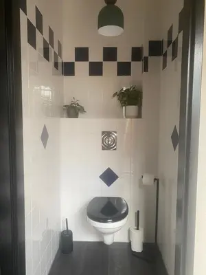 a bathroom with a toilet with a black seat at Guesthouse Katwijk aan Zee in Katwijk aan Zee
