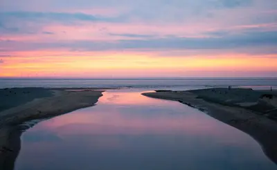 a view of a body of water at sunset at Guesthouse Katwijk aan Zee in Katwijk aan Zee