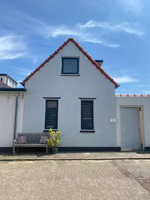 a white house with a bench in front of it at Guesthouse Katwijk aan Zee in Katwijk aan Zee