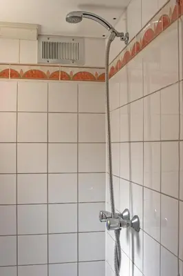 a shower in a bathroom with white tiles at De Mallemoolen in Amsterdam