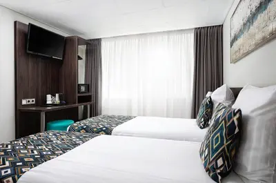 a hotel room with two beds and a tv at Hotel Damsquare in Amsterdam