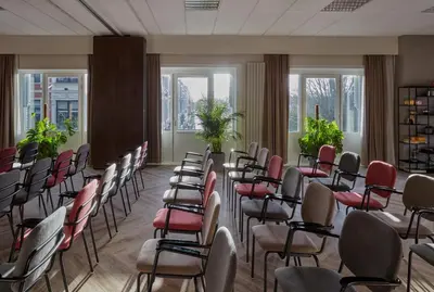 a room with chairs and tables and windows at Park Centraal Amsterdam, part of Sircle Collection in Amsterdam