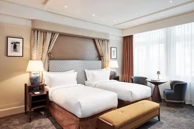 a hotel room with two beds and a desk at De L’Europe Amsterdam – The Leading Hotels of the World in Amsterdam