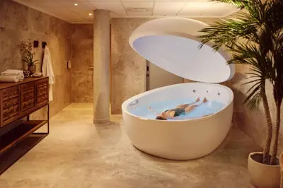 a person laying in a bath tub in a bathroom at Van der Valk Palace Hotel Noordwijk in Noordwijk aan Zee