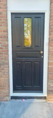 a black door on the side of a brick building at The Flower Fields in Lisse