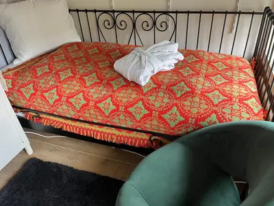 a bed with a red blanket and a green chair at BeBaBops Homestay Utrecht in Utrecht