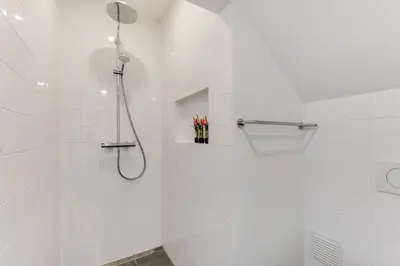 a white bathroom with a shower with a shower head at Vernieuwd Zeezicht Villa Duin Suite in Bergen aan Zee