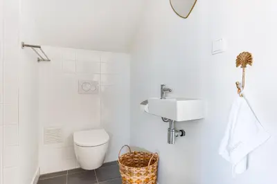 a white bathroom with a toilet and a sink at Vernieuwd Zeezicht Villa Duin Suite in Bergen aan Zee