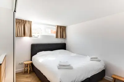a bedroom with a bed with white sheets and a mirror at Vernieuwd Zeezicht Villa Duin Suite in Bergen aan Zee