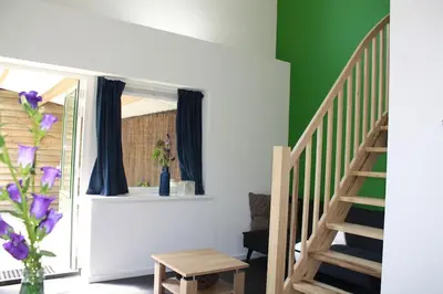 a room with a staircase and a vase with purple flowers at De Bosrand grenzend aan het bos in Castricum