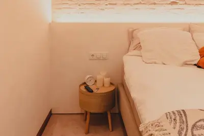 a small bedroom with a bed and a nightstand with a clock at Appartement met tuin in Haarlem centrum(Vijfhoek) in Haarlem