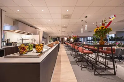 a restaurant with a long bar with stools at Postillion Utrecht Bunnik in Bunnik