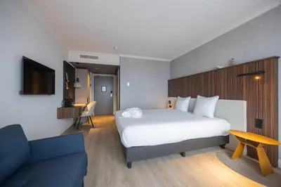 a hotel room with a large bed and a couch at Postillion Utrecht Bunnik in Bunnik