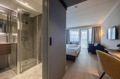 a hotel room with a bed and a shower at Postillion Utrecht Bunnik in Bunnik