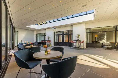 a lobby with tables and chairs and a skylight at Postillion Utrecht Bunnik in Bunnik