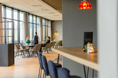 a group of people sitting at tables in a cafeteria at Postillion Utrecht Bunnik in Bunnik