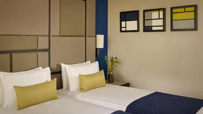a bedroom with a white bed with yellow pillows at Park Plaza Utrecht in Utrecht