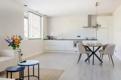 a white kitchen with a dining table and chairs at SéSé in Vinkeveen