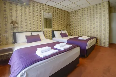 two beds in a room with purple and white at Hotel Zwanenburg Amsterdam Airport in Zwanenburg