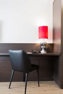 a desk with a chair and a red lamp on it at Bastion Hotel Almere in Almere