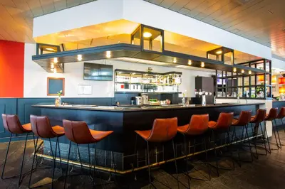 a bar in a restaurant with orange bar stools at Bastion Hotel Almere in Almere