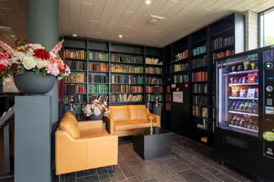 a library with two chairs and a drink refrigerator at Bastion Hotel Almere in Almere