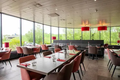 a restaurant with tables and chairs and large windows at Bastion Hotel Almere in Almere