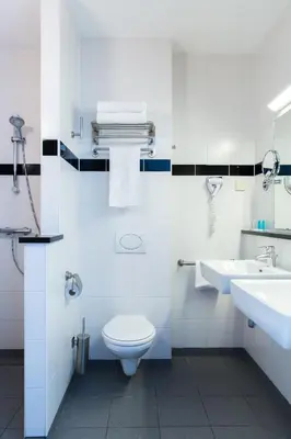 a white bathroom with a toilet and two sinks at Best Western Plus Amsterdam Airport Hotel in Hoofddorp