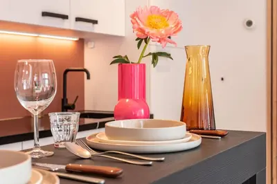 a table with a pink vase and plates and glasses at Boutique Studio Amsterdam near RAI and De Pijp in Amsterdam
