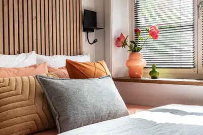 a bedroom with a bed with pillows and a window with flowers at Boutique Studio Amsterdam near RAI and De Pijp in Amsterdam