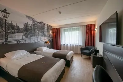 a hotel room with two beds and a flat screen tv at Bastion Hotel Amsterdam Amstel in Amsterdam