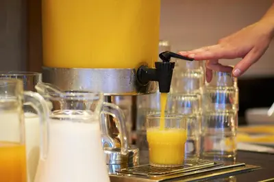 a person is making a glass of orange juice at Bastion Hotel Amsterdam Amstel in Amsterdam