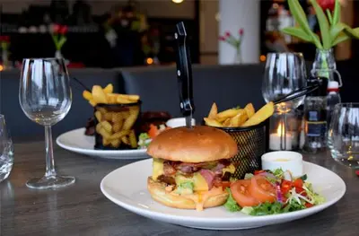 a plate with a sandwich and french fries on a table at Bastion Hotel Amsterdam Amstel in Amsterdam