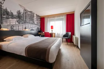 a hotel room with a large bed and red curtains at Bastion Hotel Amsterdam Amstel in Amsterdam