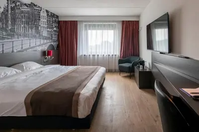 a hotel room with a large bed and a desk at Bastion Hotel Amsterdam Amstel in Amsterdam